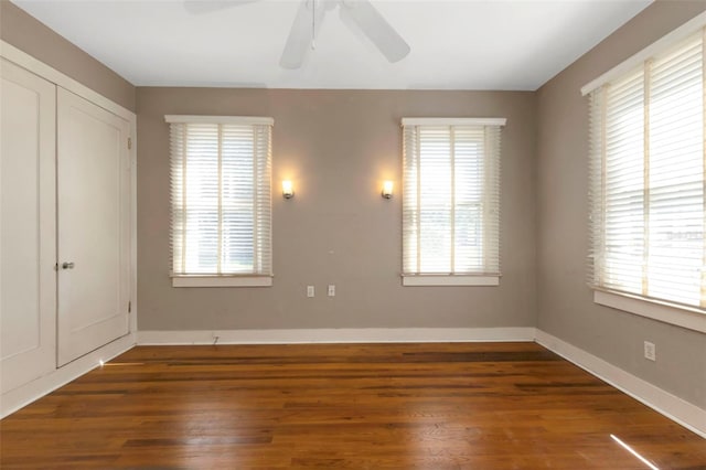 unfurnished bedroom featuring multiple windows, baseboards, and wood finished floors