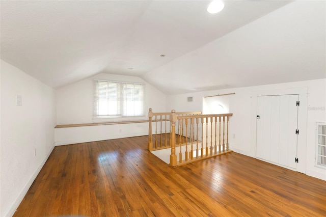 additional living space featuring lofted ceiling, baseboards, visible vents, and hardwood / wood-style floors