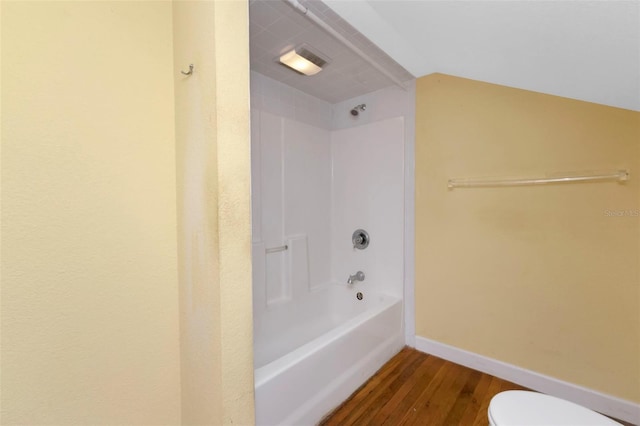 bathroom with shower / bath combination, toilet, vaulted ceiling, wood finished floors, and baseboards