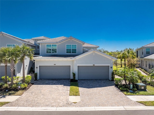 view of front of home featuring an attached garage, a tile roof, and decorative driveway