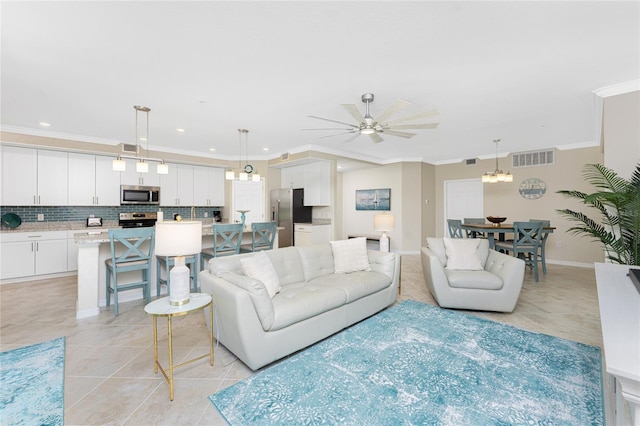 living room featuring light tile patterned floors, visible vents, and crown molding