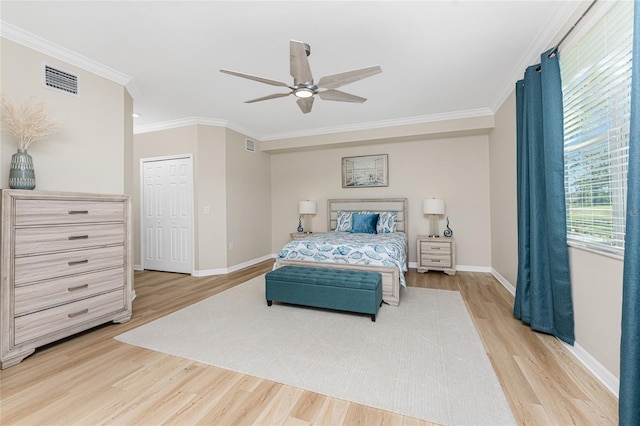 bedroom with baseboards, visible vents, light wood finished floors, and ornamental molding