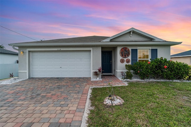 ranch-style house featuring an attached garage, a front yard, decorative driveway, and stucco siding