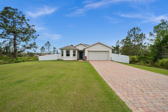 single story home with an attached garage, fence, decorative driveway, and a front yard