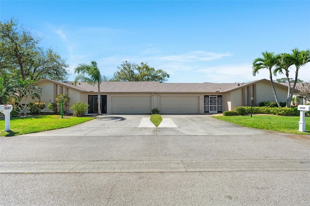 view of front of house featuring an attached garage, stucco siding, driveway, and a front yard