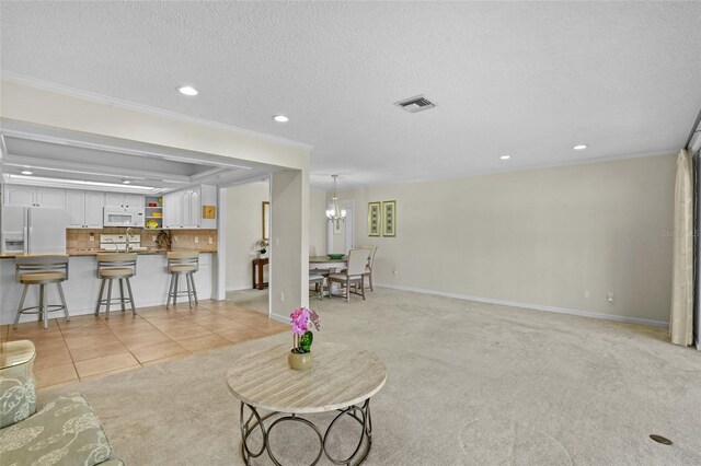 living area featuring light tile patterned floors, light colored carpet, visible vents, ornamental molding, and a textured ceiling