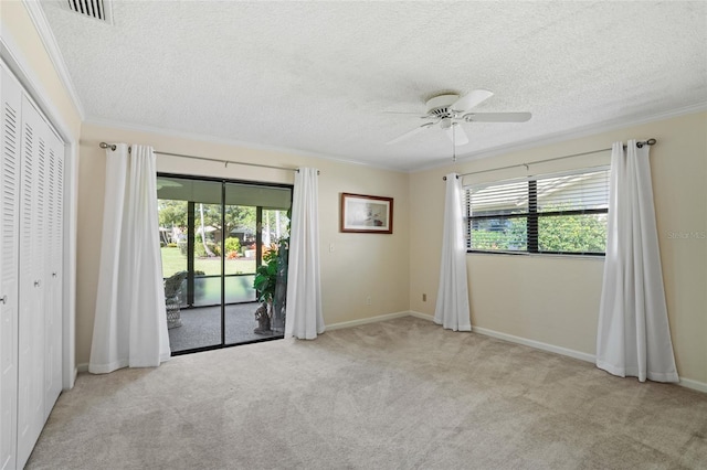 carpeted empty room with ornamental molding, visible vents, and plenty of natural light