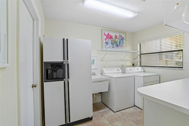 laundry area featuring laundry area, light tile patterned floors, washer and clothes dryer, a textured ceiling, and a sink