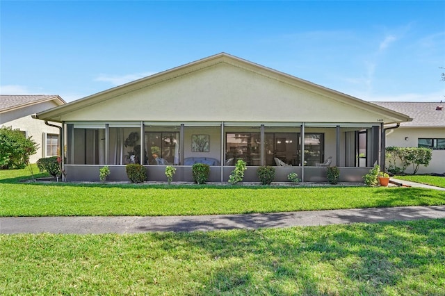 rear view of property featuring a sunroom, a lawn, and stucco siding