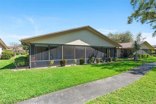 view of side of property featuring a lawn, a sunroom, and stucco siding