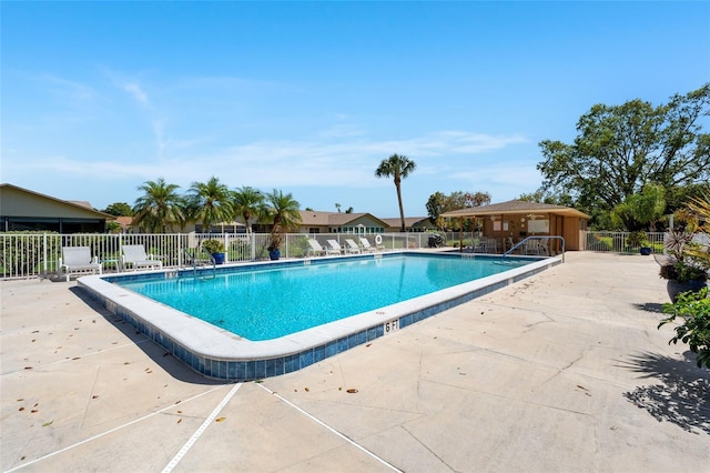 pool with a patio area and fence