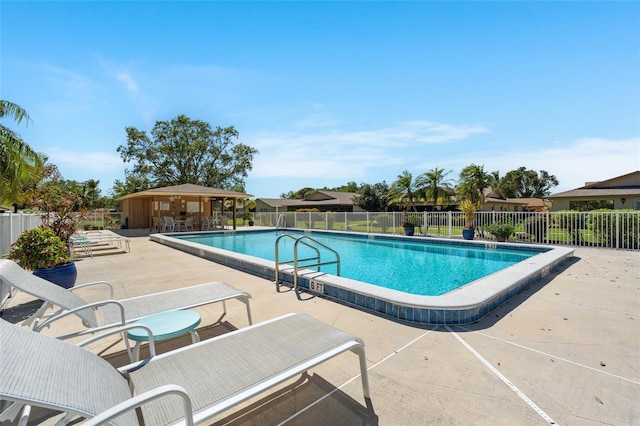 pool with a patio, an outdoor structure, and fence