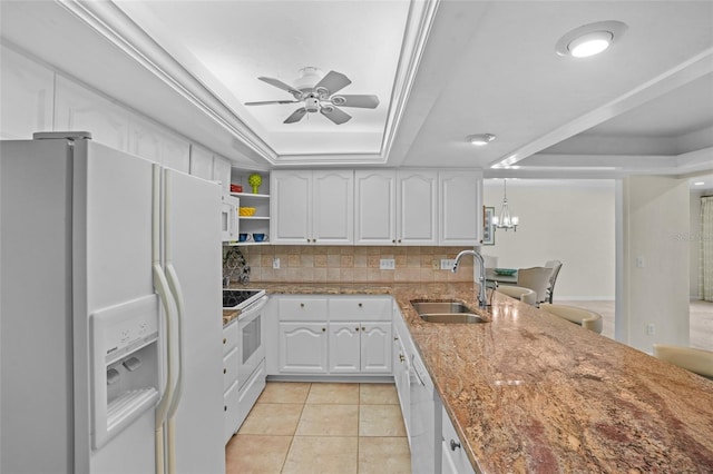 kitchen featuring white appliances, tasteful backsplash, a raised ceiling, white cabinetry, and a sink