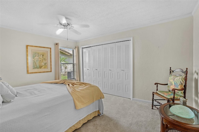 carpeted bedroom featuring baseboards, ceiling fan, crown molding, a textured ceiling, and a closet