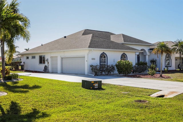 ranch-style home with concrete driveway, an attached garage, a front lawn, and roof with shingles