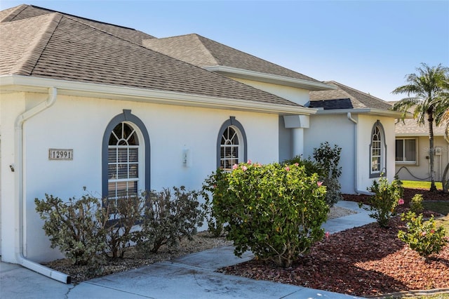 view of property exterior with stucco siding and a shingled roof