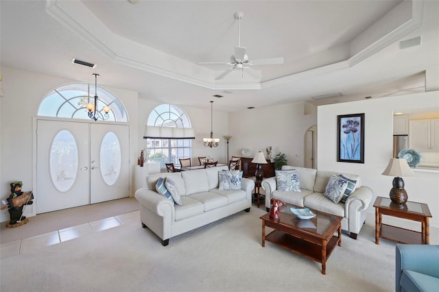 living room featuring arched walkways, visible vents, a tray ceiling, and light tile patterned flooring