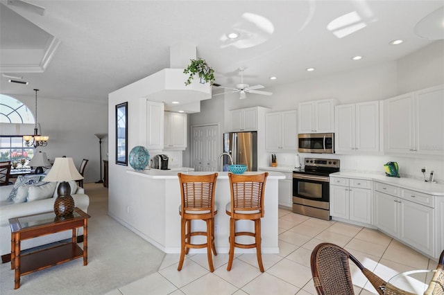 kitchen featuring a breakfast bar area, light countertops, ceiling fan with notable chandelier, white cabinets, and stainless steel appliances