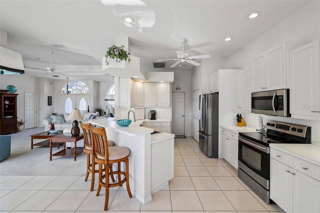 kitchen featuring open floor plan, a breakfast bar, a peninsula, light tile patterned flooring, and stainless steel appliances