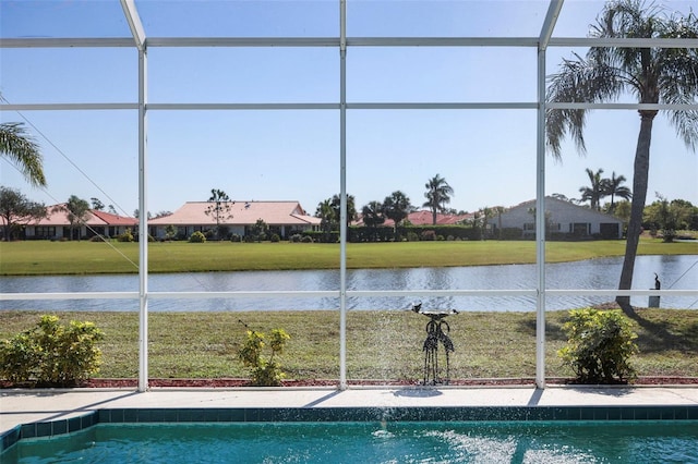 view of pool featuring glass enclosure, a lawn, and a water view