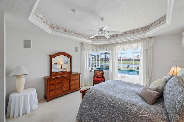 carpeted bedroom featuring a textured ceiling, a raised ceiling, and a ceiling fan