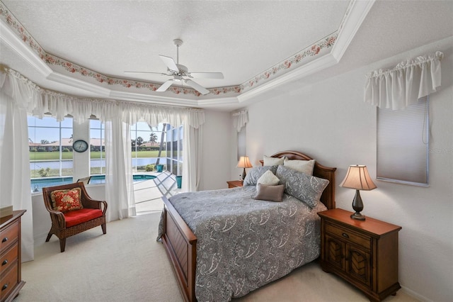 bedroom with ceiling fan, a textured ceiling, a raised ceiling, access to outside, and light colored carpet