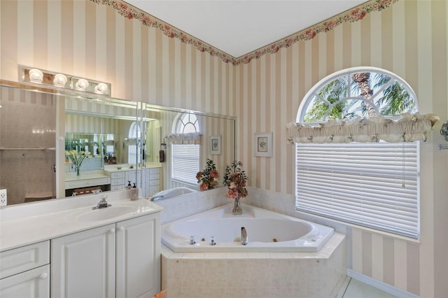 bathroom with wallpapered walls, a jetted tub, and vanity