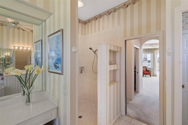 bathroom with a tile shower, tile patterned flooring, wallpapered walls, and a ceiling fan