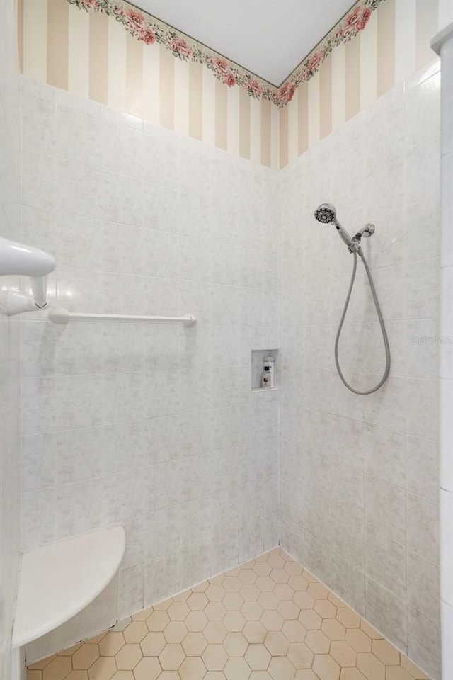 full bathroom with tiled shower and wallpapered walls