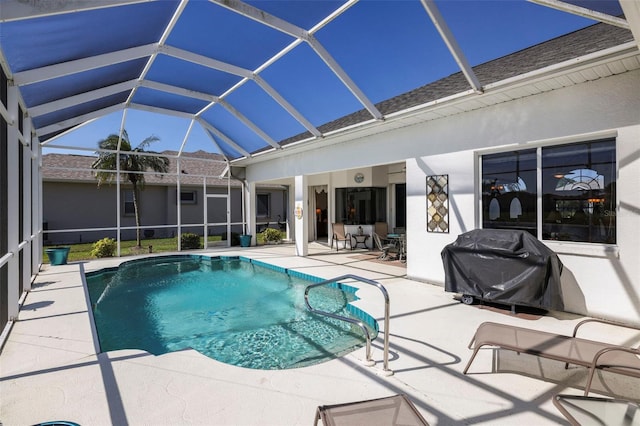 outdoor pool with glass enclosure, area for grilling, and a patio area