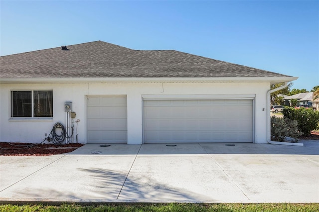 exterior space featuring a garage, driveway, and a shingled roof