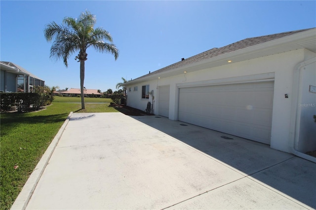 view of side of home with concrete driveway, a yard, and stucco siding