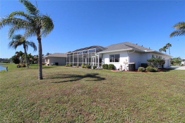 back of property featuring a lanai, central AC unit, a yard, and stucco siding