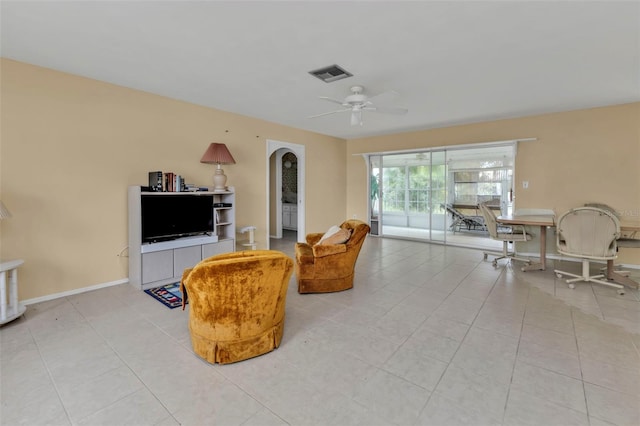 living room with visible vents, arched walkways, light tile patterned floors, baseboards, and ceiling fan