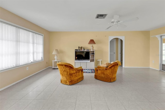 sitting room with visible vents, baseboards, light tile patterned floors, arched walkways, and a ceiling fan