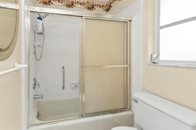 bathroom featuring combined bath / shower with glass door and toilet