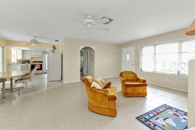 interior space featuring arched walkways, light tile patterned floors, baseboards, and ceiling fan