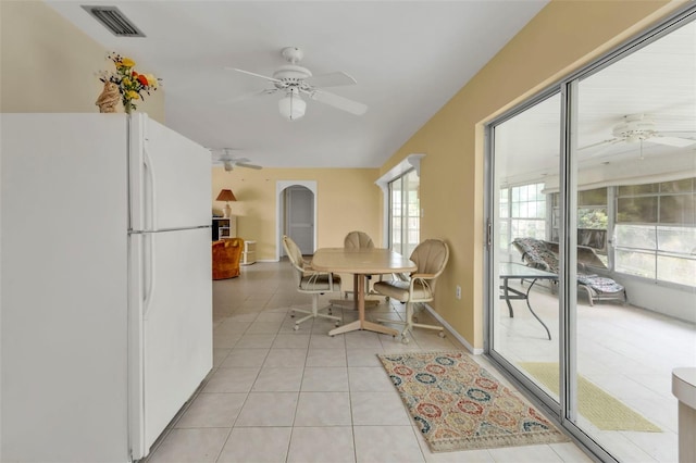 dining space with light tile patterned floors, a ceiling fan, visible vents, and arched walkways