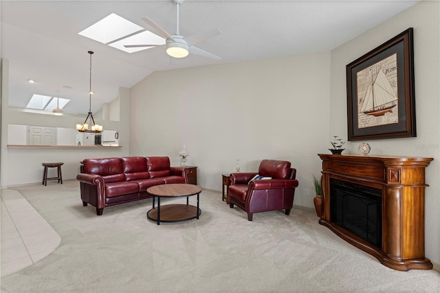 living room with ceiling fan with notable chandelier, vaulted ceiling with skylight, carpet, and a fireplace