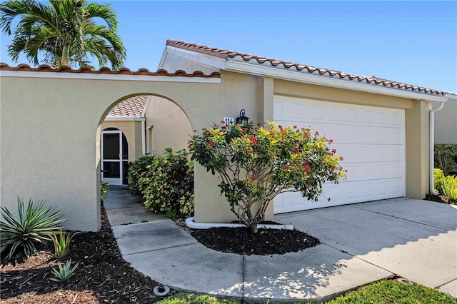 view of front of property with concrete driveway, an attached garage, a tile roof, and stucco siding