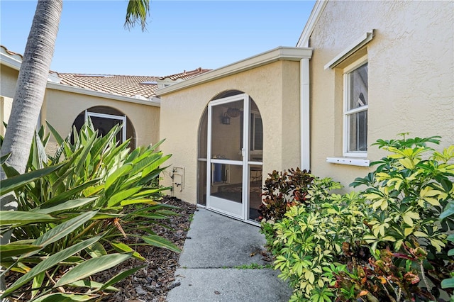 entrance to property featuring a tile roof and stucco siding