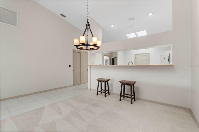 kitchen featuring pendant lighting, light tile patterned floors, visible vents, light carpet, and a kitchen breakfast bar