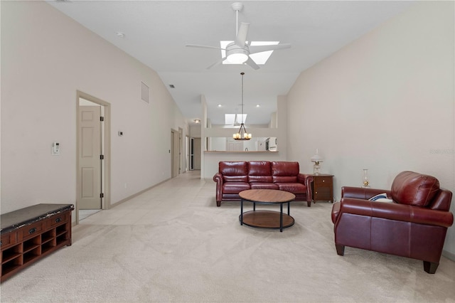 living room featuring high vaulted ceiling, ceiling fan with notable chandelier, a skylight, visible vents, and carpet