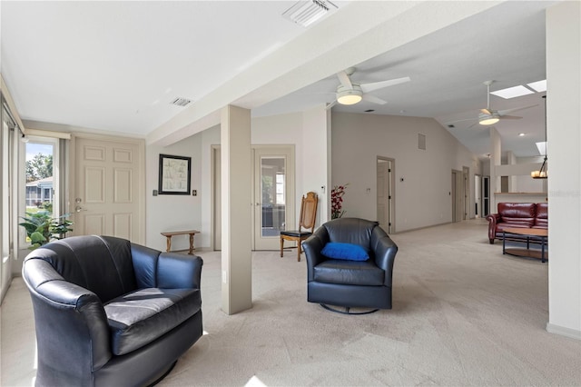 living area with lofted ceiling with skylight, light colored carpet, visible vents, and a ceiling fan