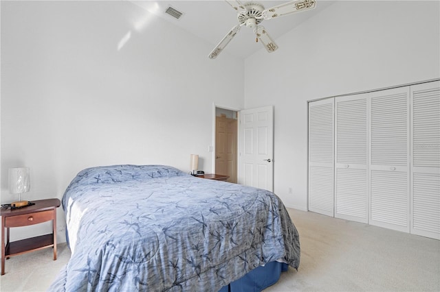 bedroom featuring light carpet, visible vents, a ceiling fan, a high ceiling, and a closet