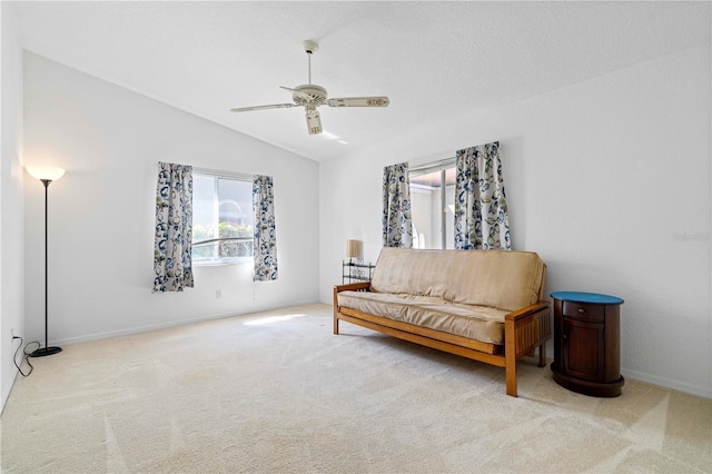 living area featuring lofted ceiling, carpet, baseboards, and a ceiling fan