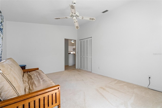 living area with visible vents, a ceiling fan, and light colored carpet