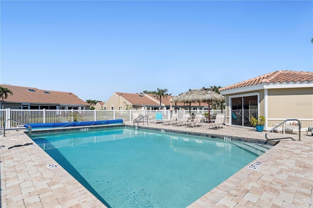 community pool featuring a residential view, a patio, and fence