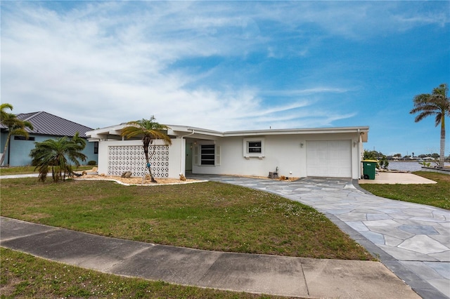 ranch-style house with stucco siding, an attached garage, and a front yard