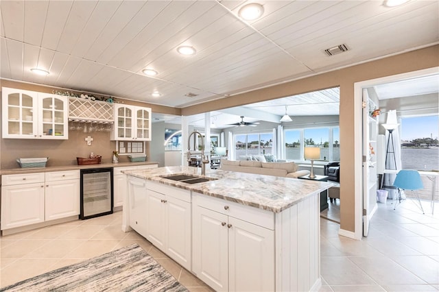 kitchen with visible vents, light tile patterned flooring, a sink, wine cooler, and glass insert cabinets